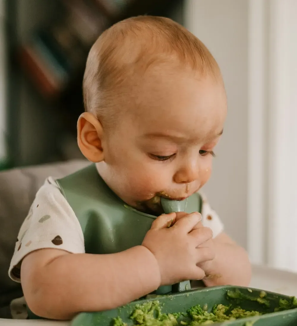 Baby isst beim Baby-led Weaning selbstständig im Hochstuhl